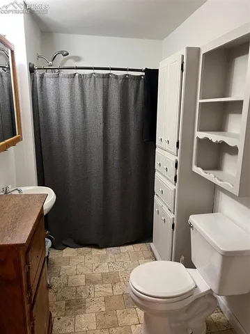 a bathroom with a sink a toilet a mirror and shower curtain