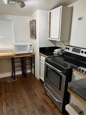 a kitchen with a stove wooden floor and a window