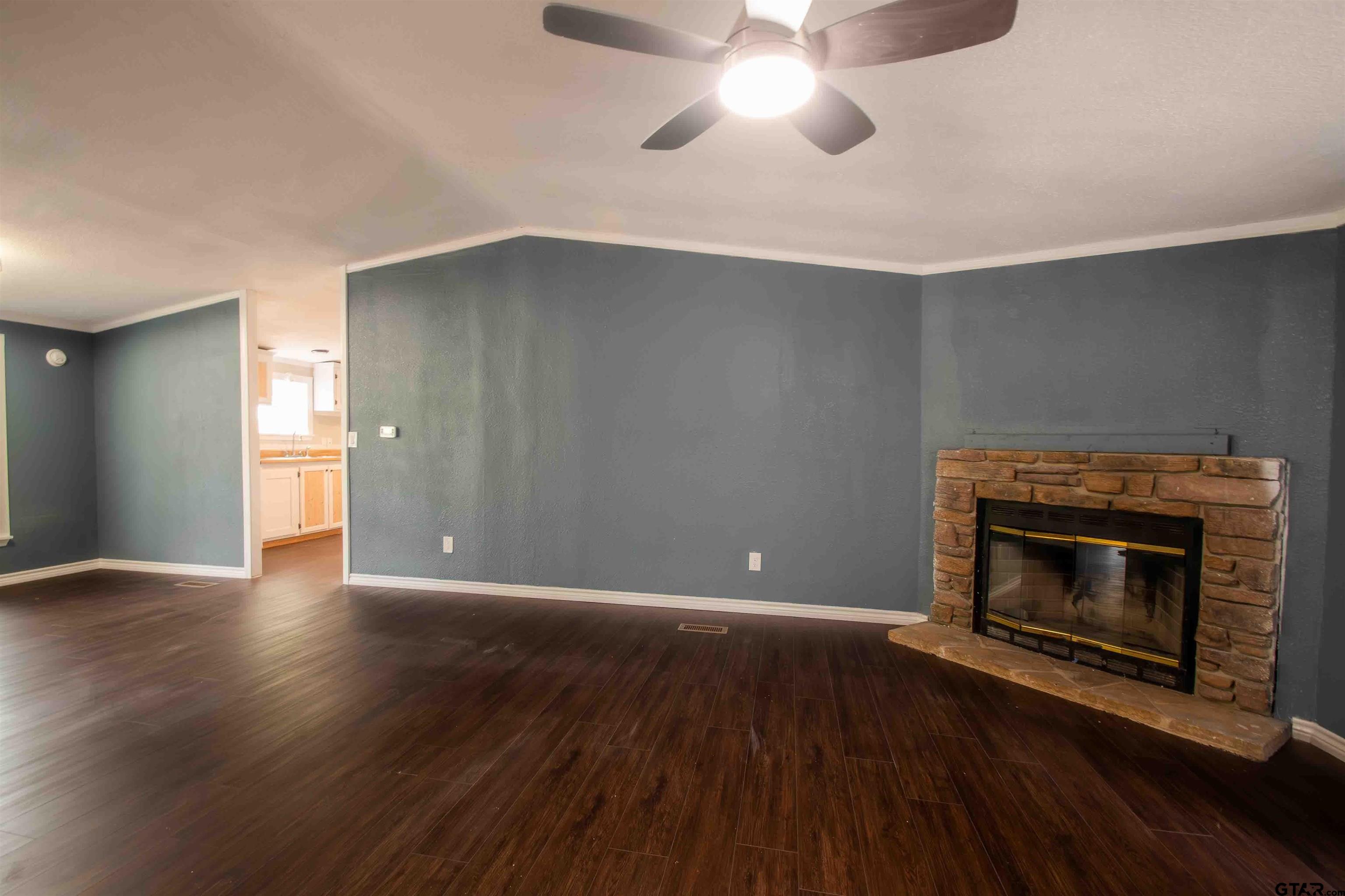 161 Clearview Circle Murchison, TX 75778 - Photo 18 of 47 an empty room with wooden floor fireplace and windows