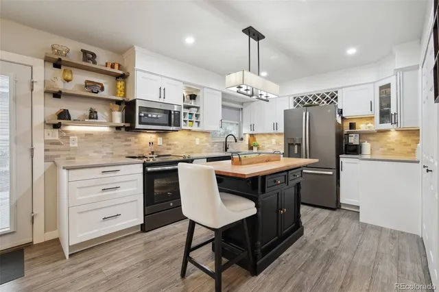 a kitchen with stainless steel appliances kitchen island granite countertop a table chairs in it and wooden floors