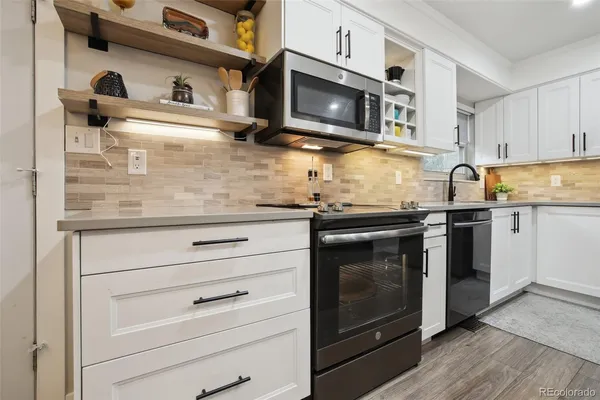 a kitchen with granite countertop white cabinets stainless steel appliances and wooden floor