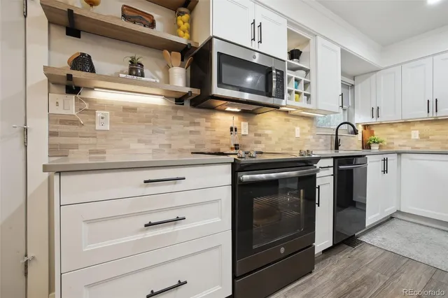 a kitchen with granite countertop white cabinets stainless steel appliances and wooden floor
