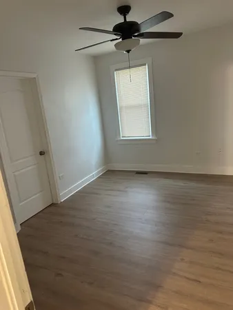 an empty room with wooden floor cabinet and windows