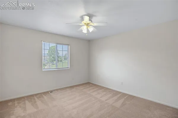 an empty room with a window and a ceiling fan