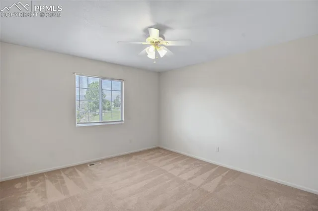 an empty room with a window and a ceiling fan