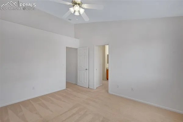 a view of an empty room with a chandelier fan