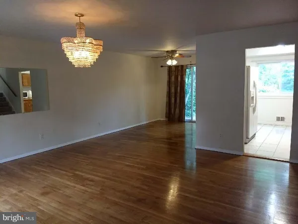an empty room with wooden floor chandelier and windows