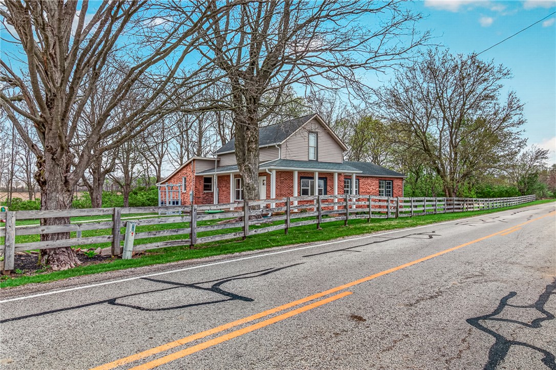 8700 Quaker Trace Road Camden, OH 45311 - Photo 2 of 34 This charming residence features a classic brick exterior and a welcoming front porch, nestled beside a rustic fence.