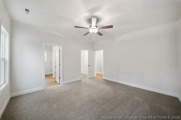 an empty room with chandelier fan and windows