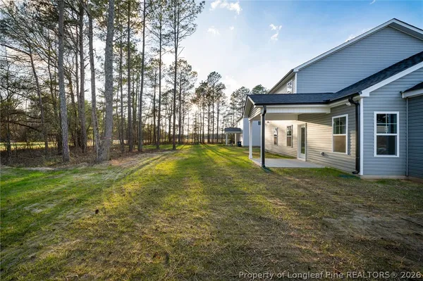 a view of a house with backyard and trees