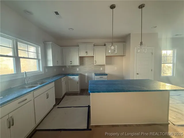 a large kitchen with kitchen island a stove a sink a center island and cabinets
