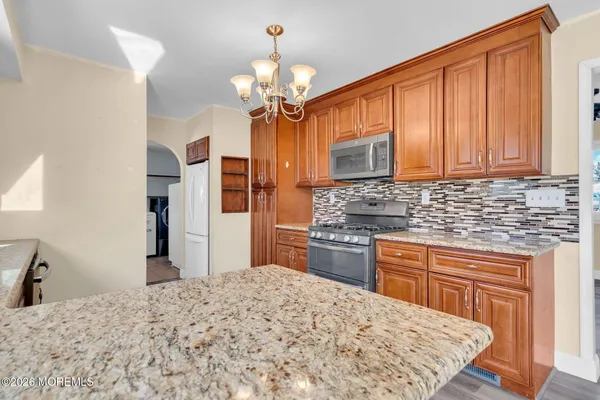 a kitchen with stainless steel appliances kitchen island granite countertop a refrigerator and a stove top oven