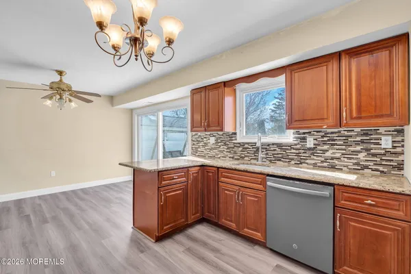 a kitchen with stainless steel appliances granite countertop a sink dishwasher a stove and a dining table with wooden floor