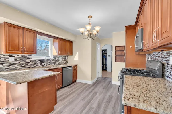 a large kitchen with stainless steel appliances kitchen island granite countertop a refrigerator a stove a sink and dishwasher with wooden floor