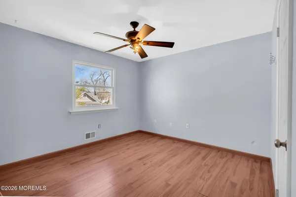 an empty room with wooden floor a ceiling fan and a ceiling fan