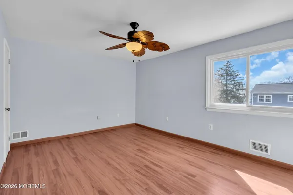 a view of an empty room with wooden floor and window