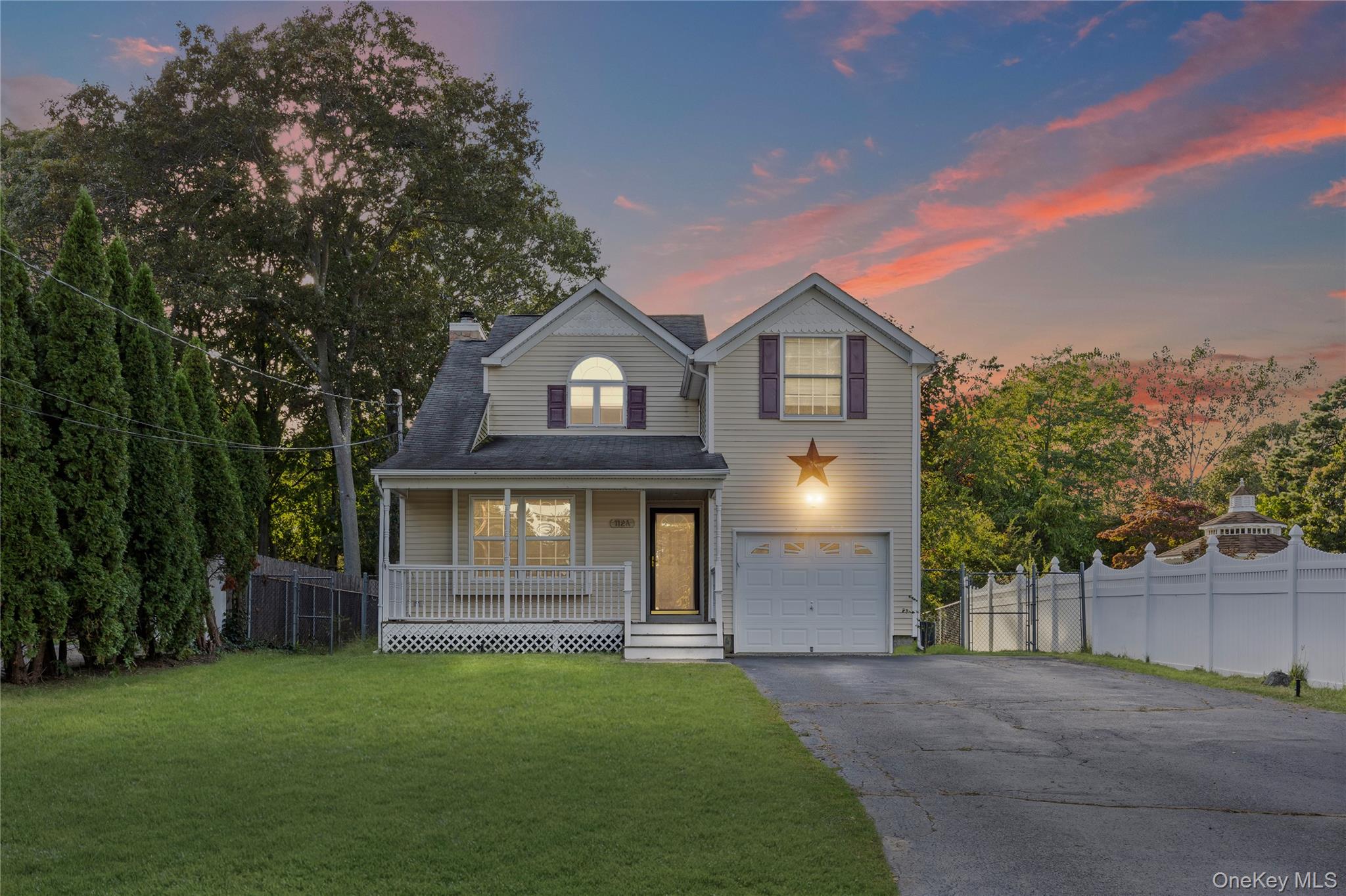 Traditional-style home featuring driveway, covered porch, a chimney, and a garage