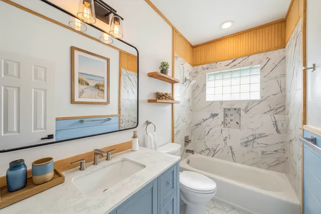 a bathroom with a bathtub sink mirror vanity and toilet