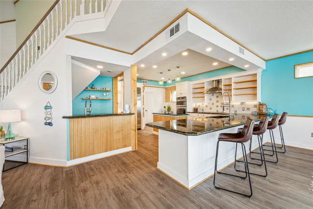 a kitchen with stainless steel appliances granite countertop a kitchen island a stove and a wooden floors