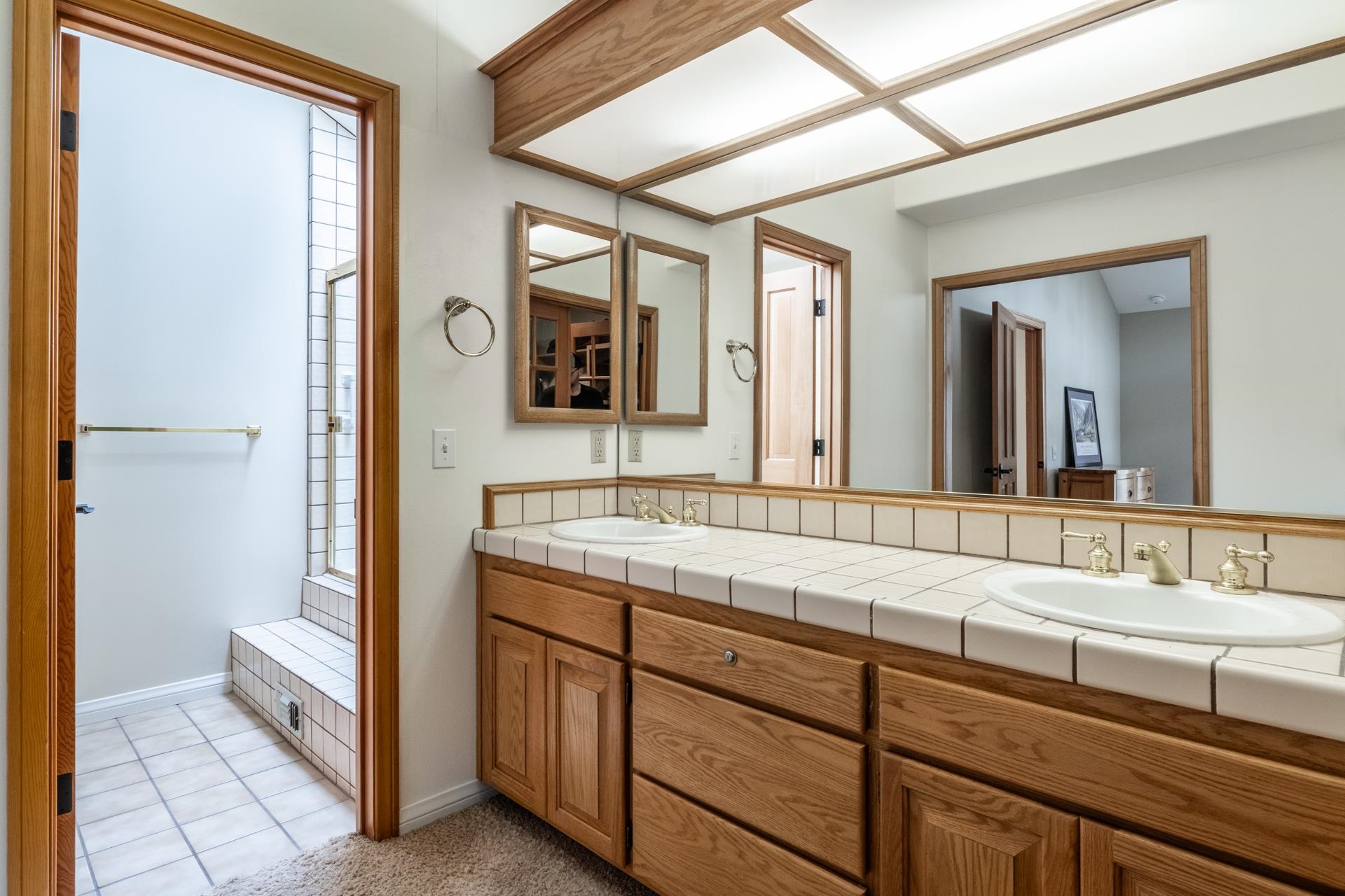272 Ridge Way Mammoth Lakes, CA 93546 - Photo 35 of 55 Bathroom vanity featuring dual under-mount sinks with brass-finish faucets, set into a tiled countertop with a matching backsplash