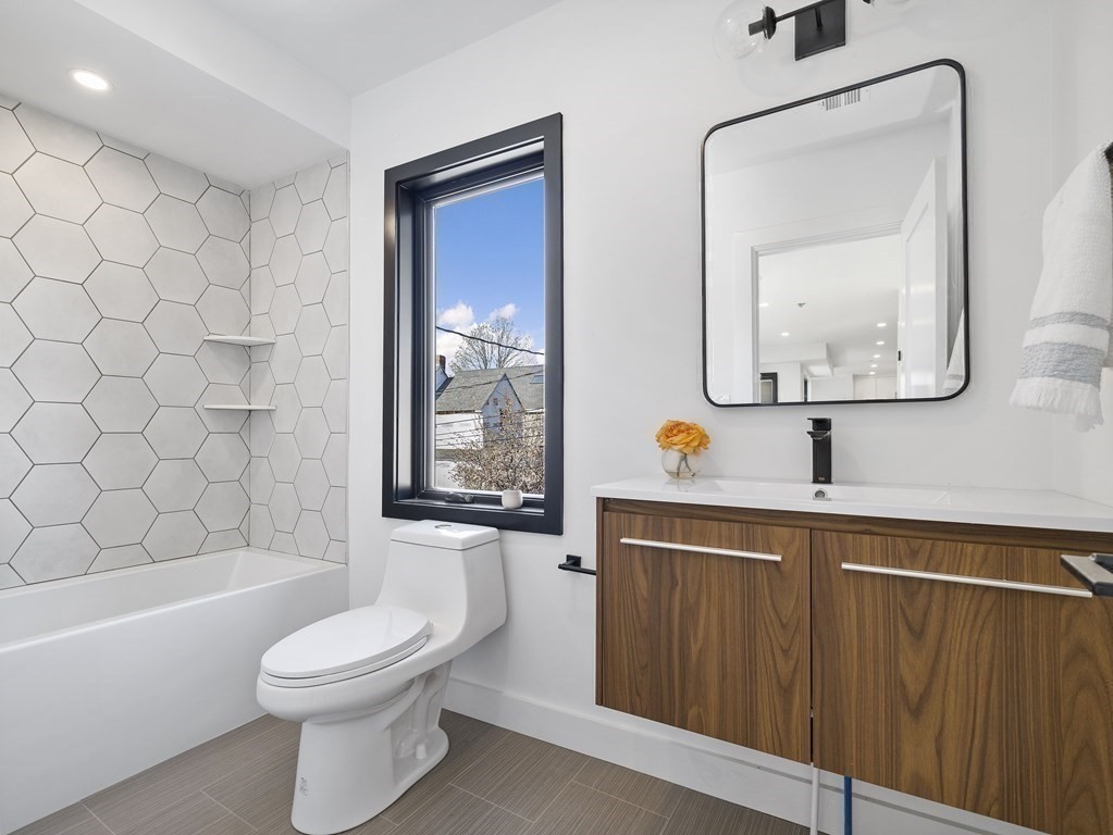 9 B Harrison Road, Unit 9B Somerville, MA 02144 - Photo 9 of 21 a bathroom with a toilet a sink a mirror a bathtub and shower