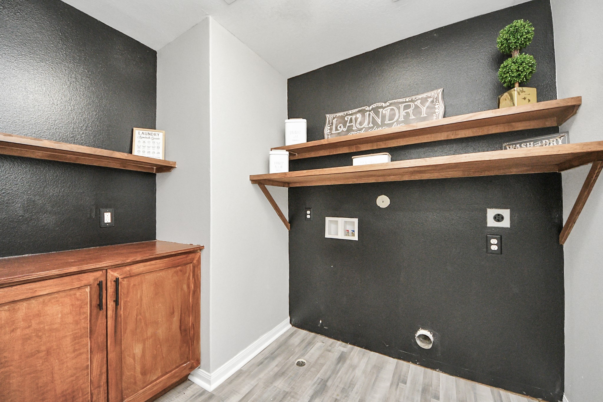 6931 Primrose Road Baytown, TX 77521 - Photo 33 of 50 Stylish laundry room with modern black accent walls, built-in shelving, and additional cabinet storage for organization.