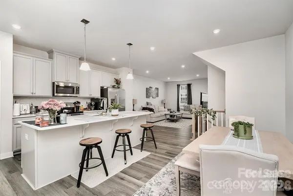 a large white kitchen with lots of counter space a sink appliances and cabinets