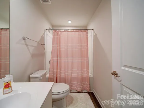 a white toilet sitting next to a bathroom sink and a shower