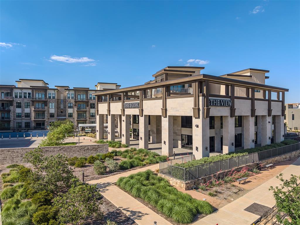 2700 Old Denton Road, Unit 1044 Carrollton, TX 75007 - Photo 32 of 33 Modern multi-story building featuring a prominent "The View" sign, stone-clad pillars, expansive windows, and a structured outdoor landscaping with pathways and various plantings