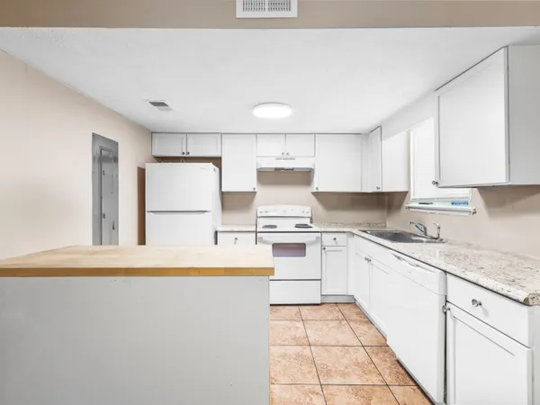 a kitchen with granite countertop white cabinets and white appliances