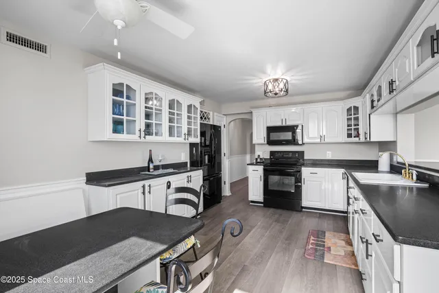 a kitchen with white cabinets and black appliances