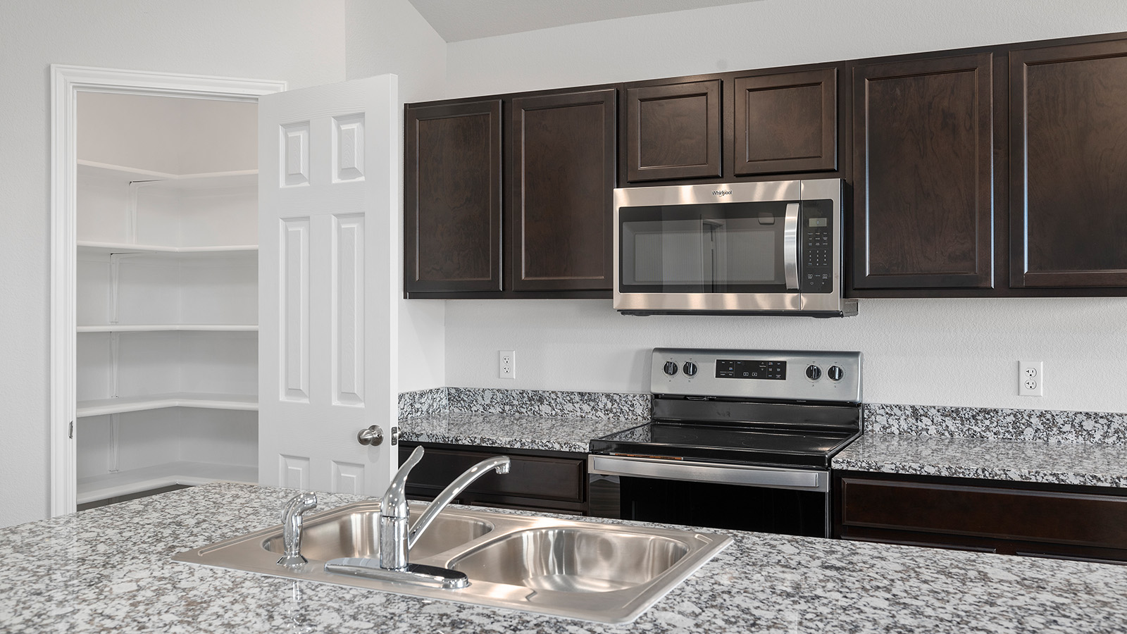 101 Rain Drop Road Jarrell, TX 76537 - Photo 6 of 22 Kitchen featuring dark wood cabinetry, stainless steel appliances, a double basin sink, and granite-finish countertops