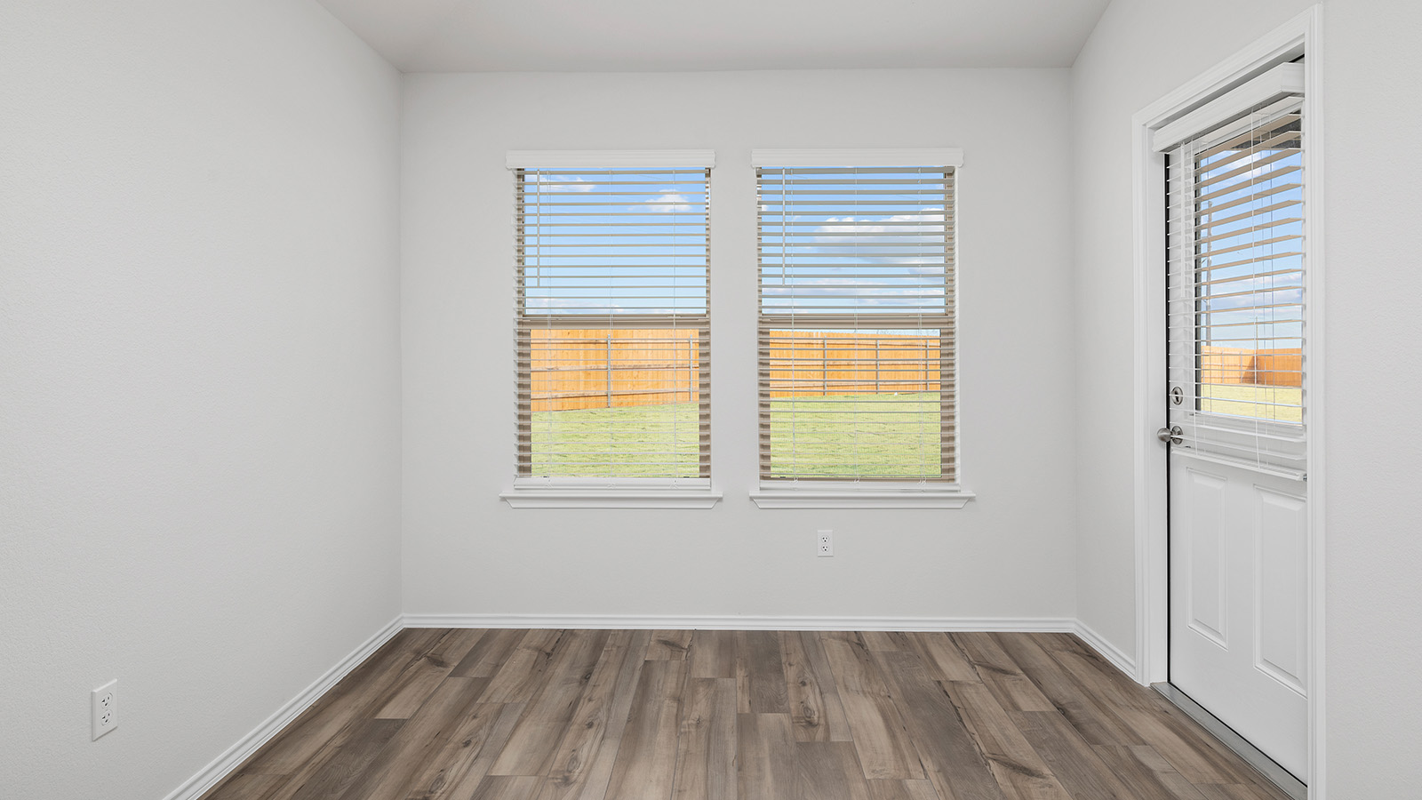 101 Rain Drop Road Jarrell, TX 76537 - Photo 7 of 22 Room featuring two windows with horizontal blinds, a white door with integrated blinds, light-colored walls, and wood-finish flooring