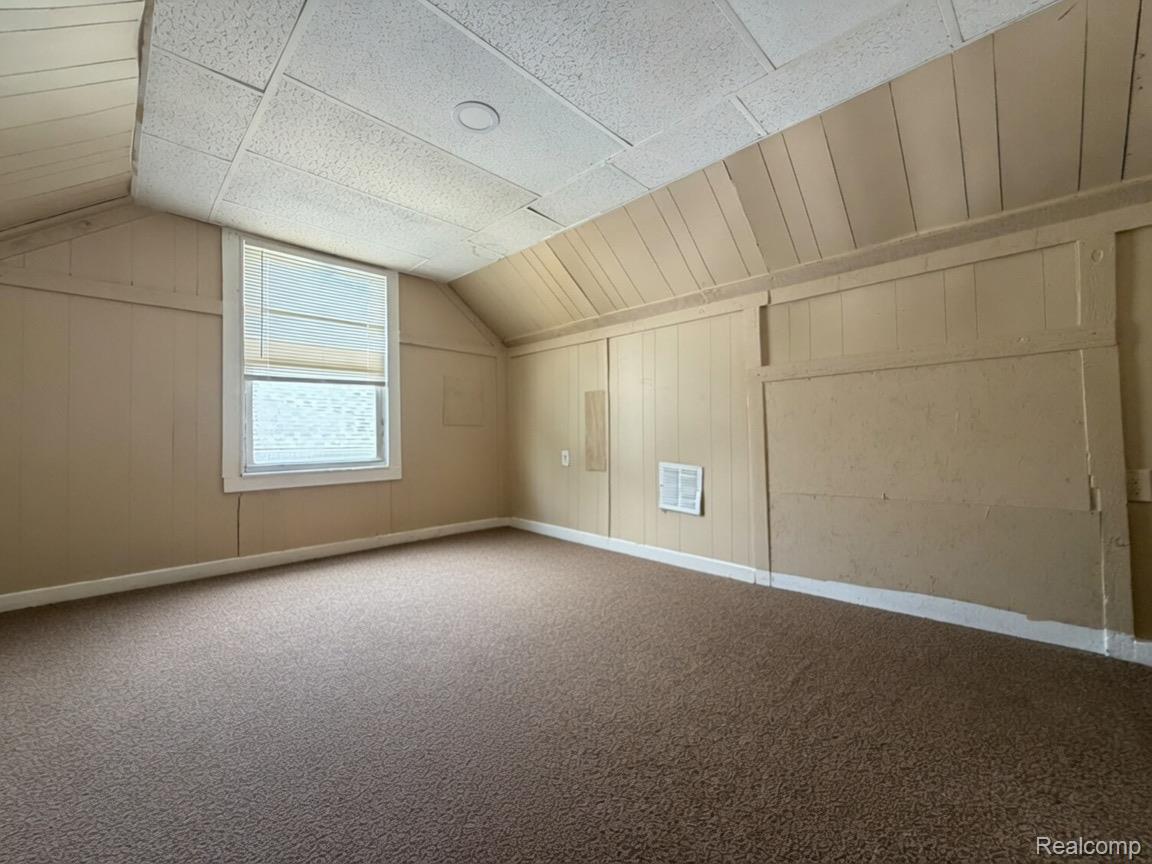 7286 Faust Avenue Detroit, MI 48228 - Photo 7 of 19 Carpeted room featuring a single window with blinds, sloped paneled walls, a white baseboard, and a textured ceiling