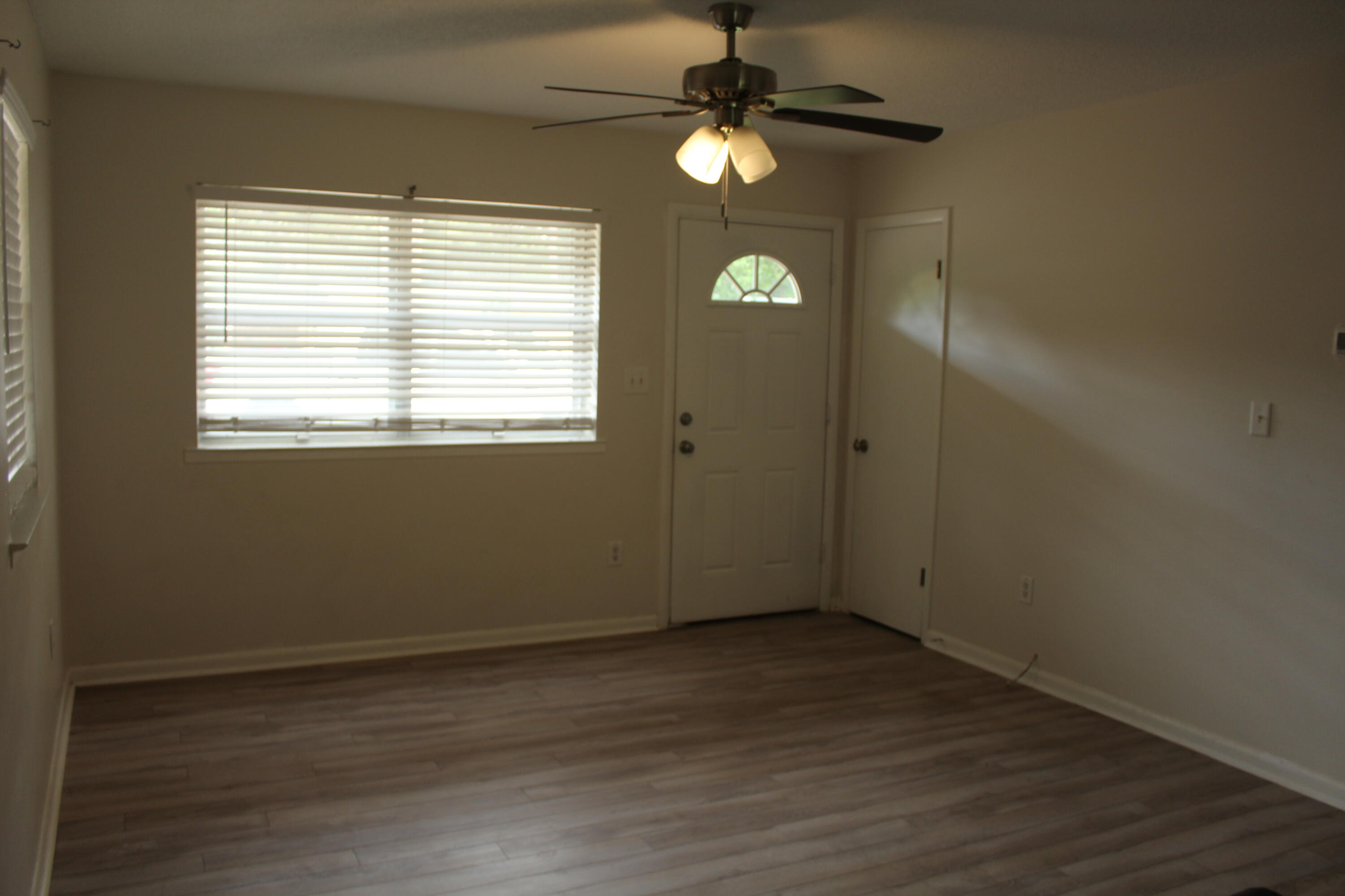313 Brackin Street, Unit A Crestview, FL 32539 - Photo 10 of 27 an empty room with wooden floor and windows