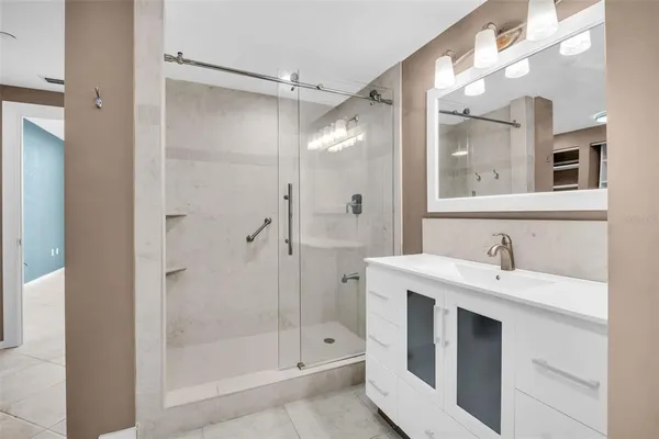 a bathroom with a shower sink vanity and mirror