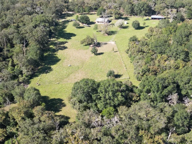 a view of a house with a big yard and large trees