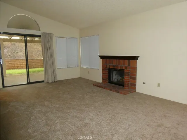 an empty room with a fireplace and large window