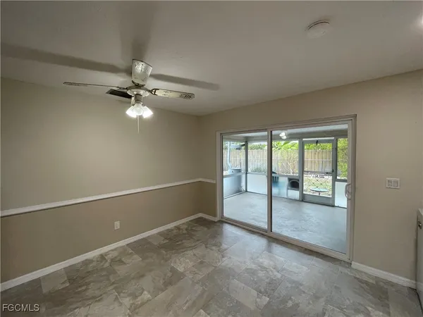 an empty room with chandelier fan and windows