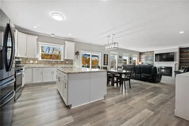 a kitchen with stainless steel appliances granite countertop a stove top oven a sink dishwasher a dining table and chairs with wooden floor