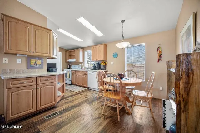 a kitchen with stainless steel appliances granite countertop a dining table chairs refrigerator sink and cabinets