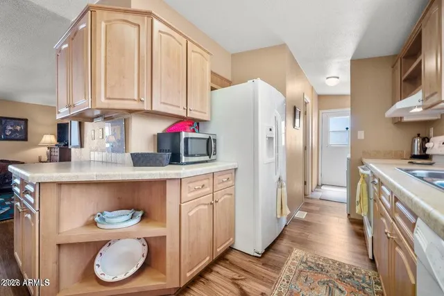 a kitchen with stainless steel appliances granite countertop a white refrigerator a sink and dishwasher with wooden floor