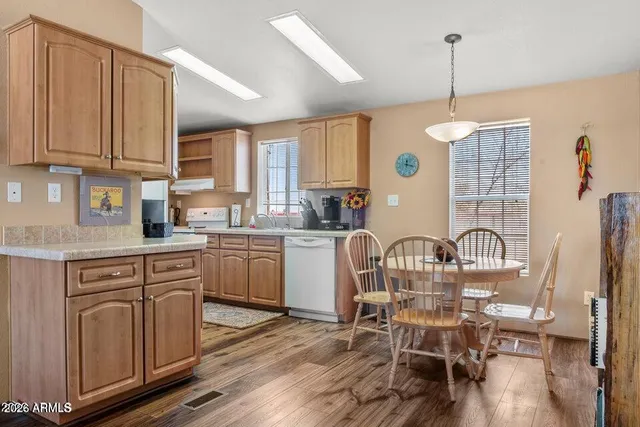 a kitchen with kitchen island granite countertop a dining table chairs sink and cabinets