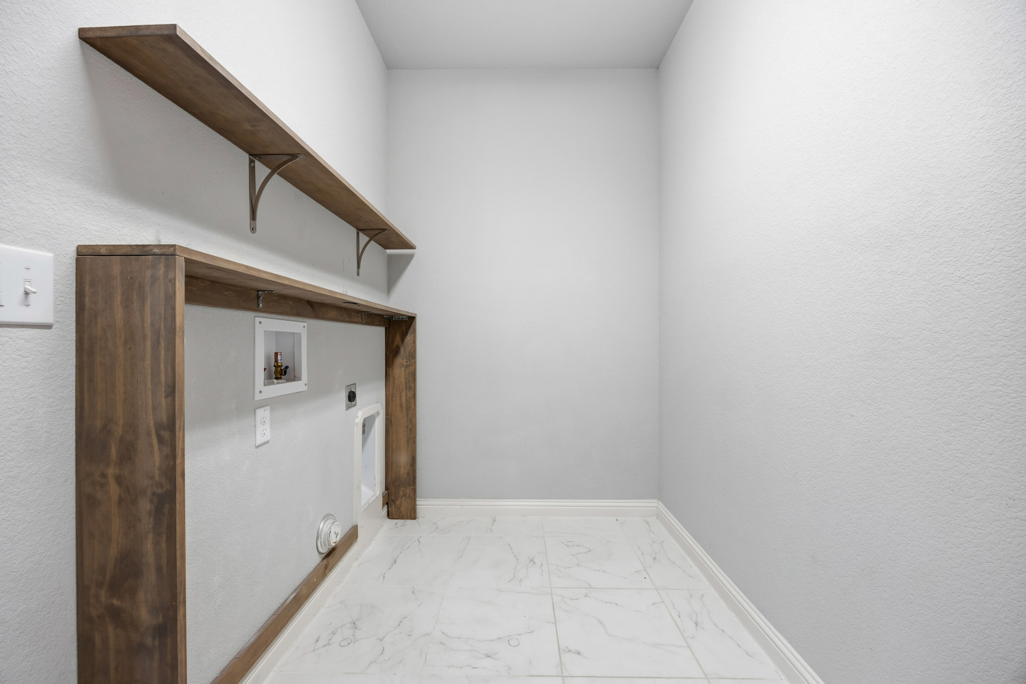 2209 Littleleaf Lane Leander, TX 78641 - Photo 12 of 27 Laundry room featuring light marble finish floors, washer hookup, hookup for an electric dryer, and a textured wall