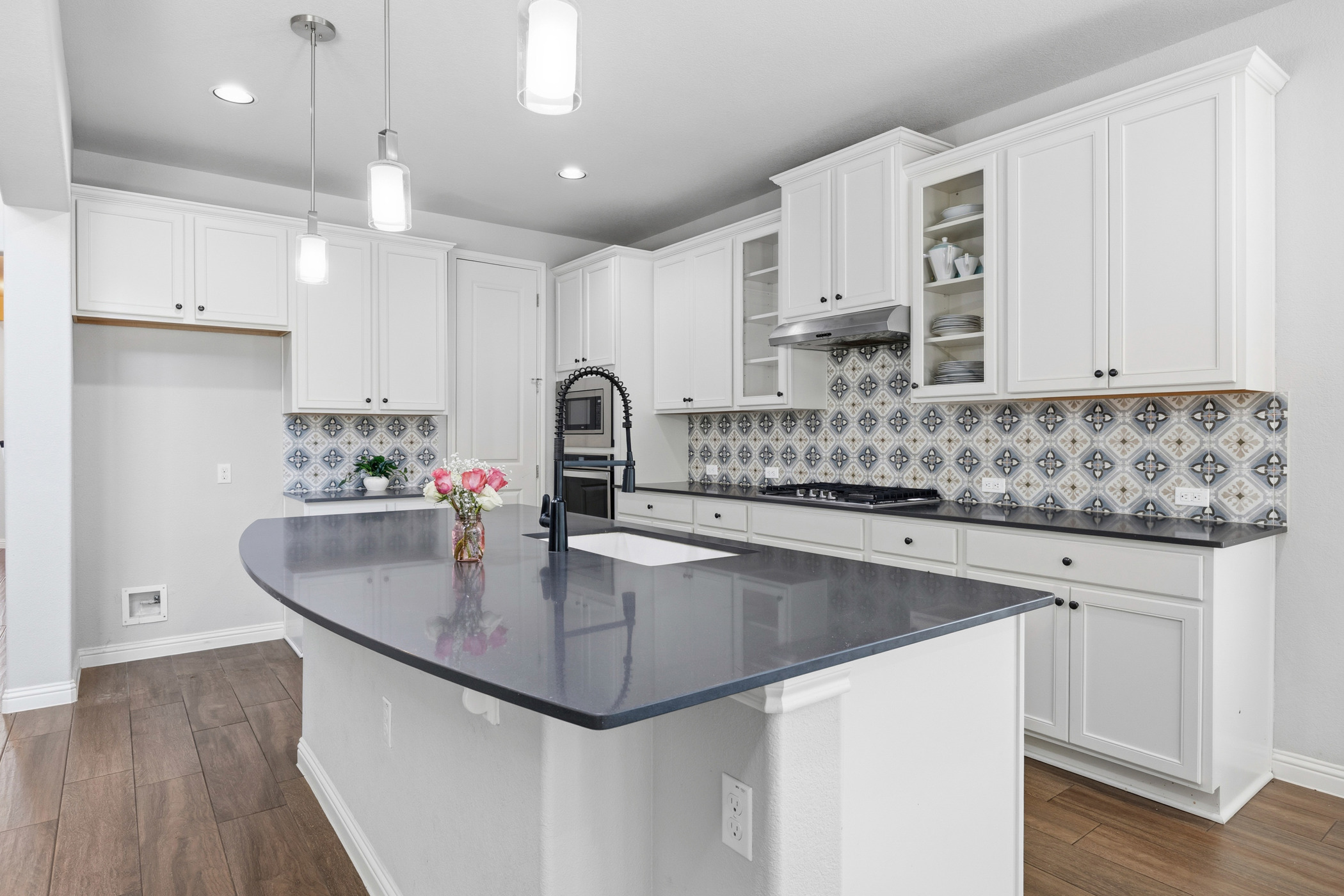 2209 Littleleaf Lane Leander, TX 78641 - Photo 3 of 27 Kitchen featuring a center island with sink, dark wood-type flooring, white cabinets, and glass insert cabinets