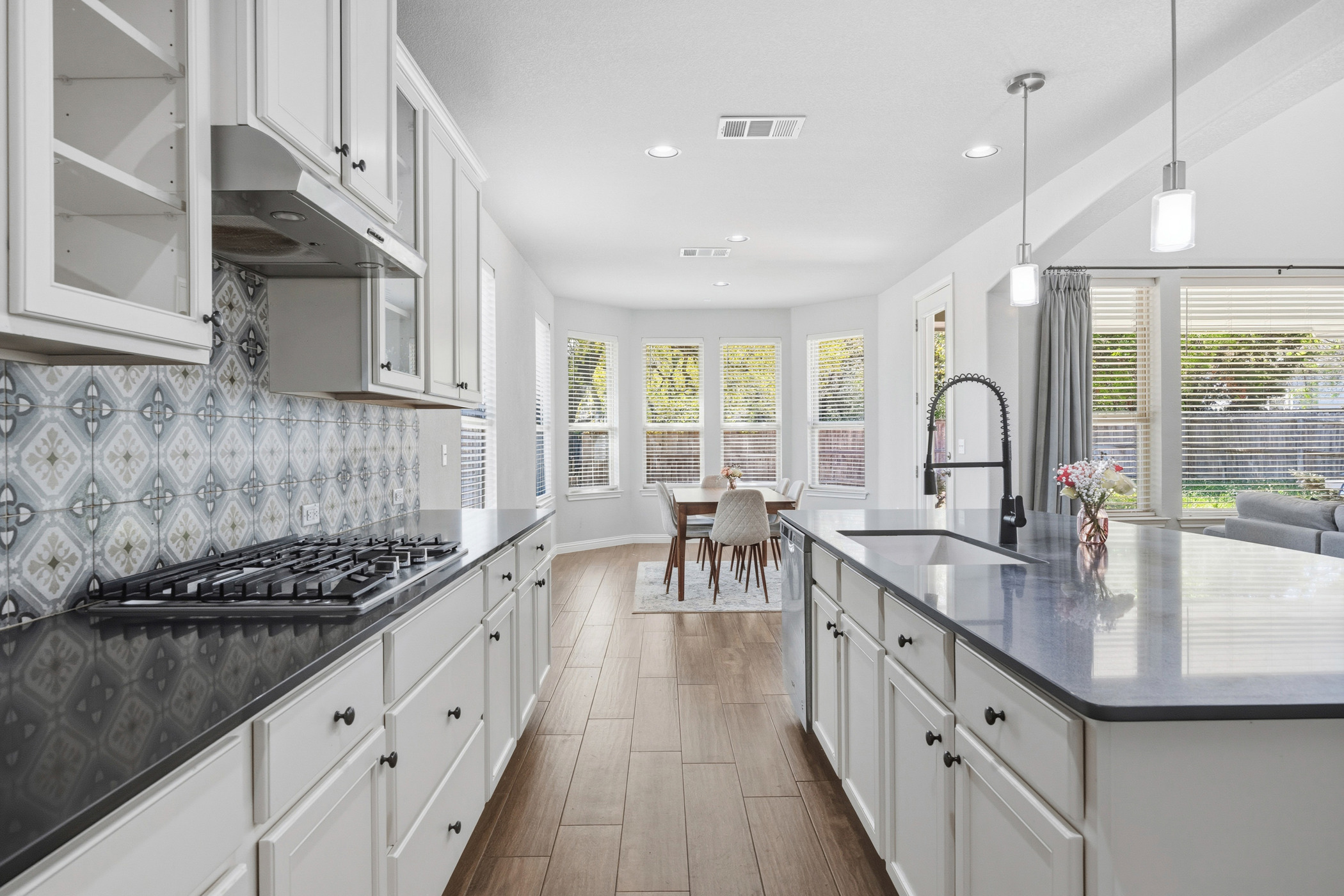 2209 Littleleaf Lane Leander, TX 78641 - Photo 5 of 27 Kitchen featuring white cabinets, glass fronted cabinets, dark wood-type flooring, dark stone counters, and stainless steel appliances