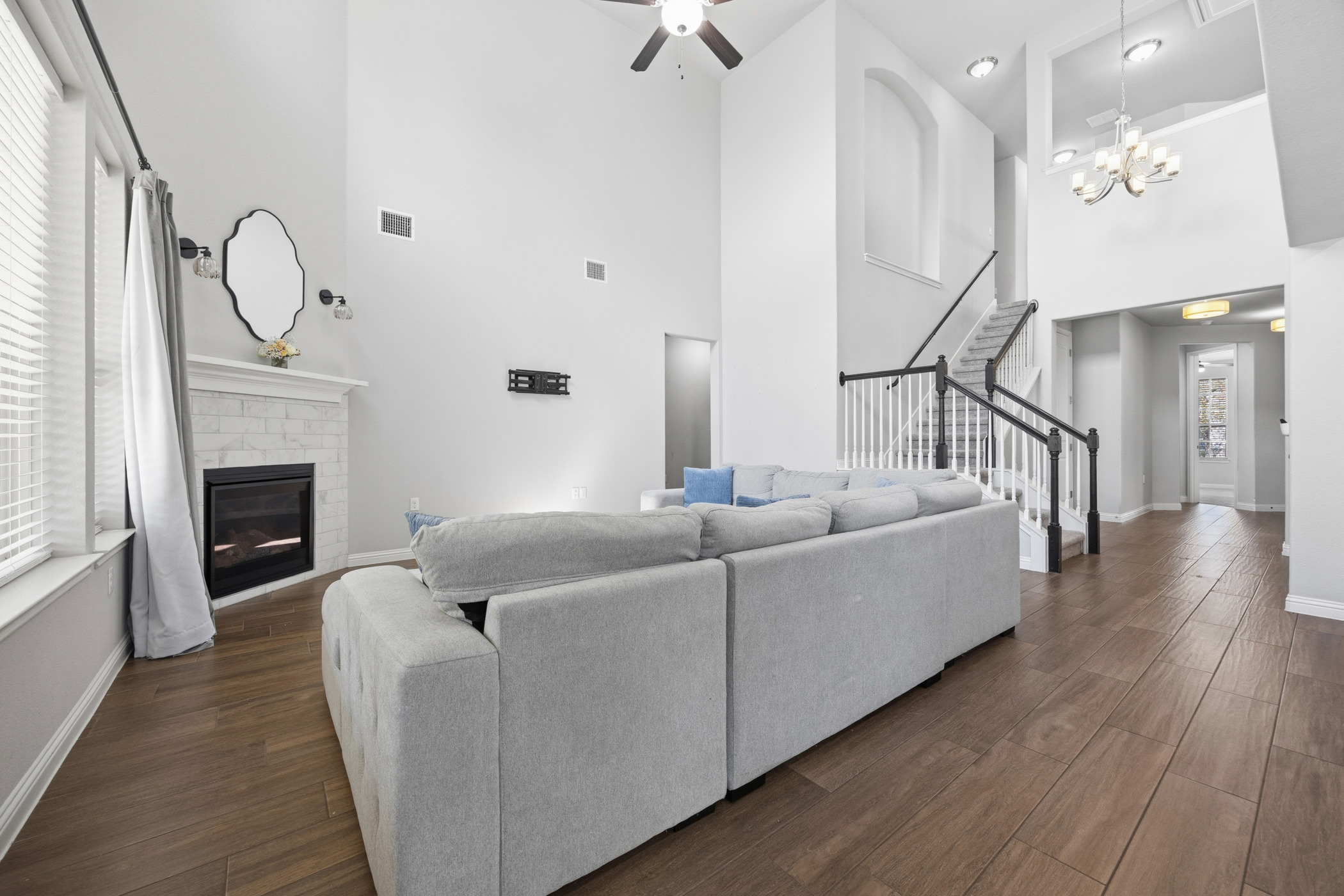 2209 Littleleaf Lane Leander, TX 78641 - Photo 7 of 27 Living area featuring a high ceiling, a ceiling fan, dark wood finished floors, a brick fireplace, and suspended lighting