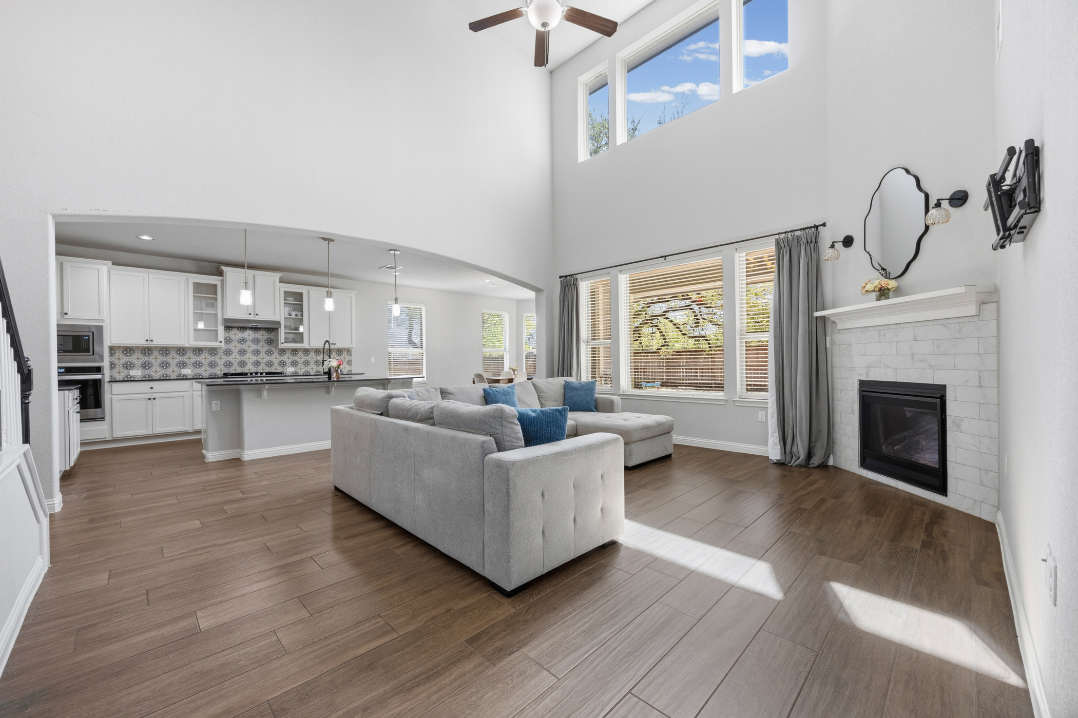2209 Littleleaf Lane Leander, TX 78641 - Photo 8 of 27 Living area featuring arched walkways, a brick fireplace, ceiling fan, dark wood-style floors, and a high ceiling
