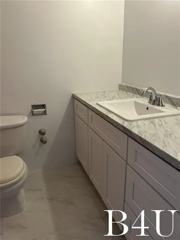 a bathroom with a granite countertop sink a toilet and a mirror