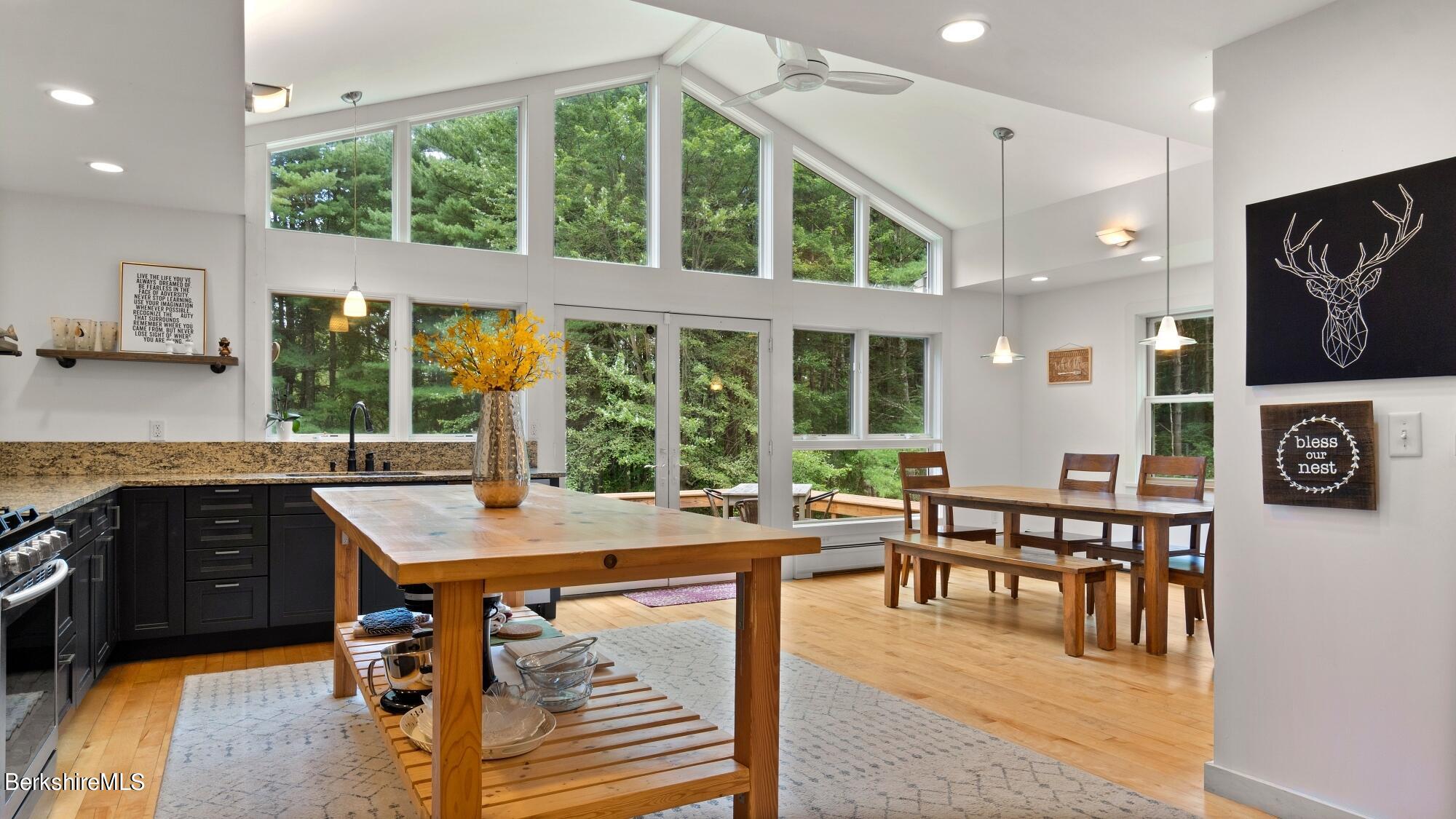 16 Squaw Peak Road Great Barrington, MA 01230 - Photo 6 of 38 a dining hall with stainless steel appliances granite countertop a stove a kitchen island a table and chairs with wooden floor